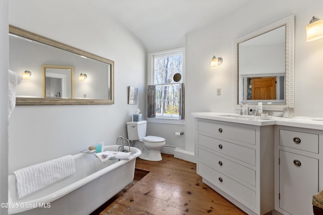 bathroom with lofted ceiling, toilet, vanity, wood-type flooring, and a soaking tub