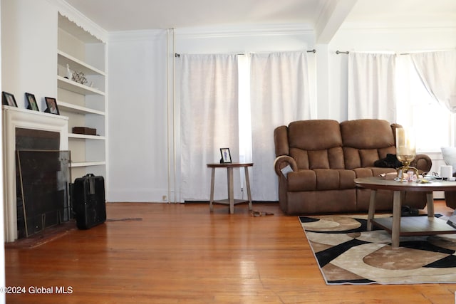 living room with crown molding, wood-type flooring, and built in shelves