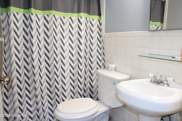 bathroom with tile walls, toilet, sink, and tasteful backsplash