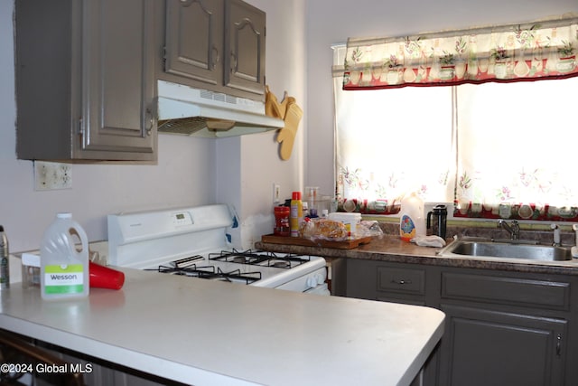 kitchen featuring gray cabinets, sink, and white gas range