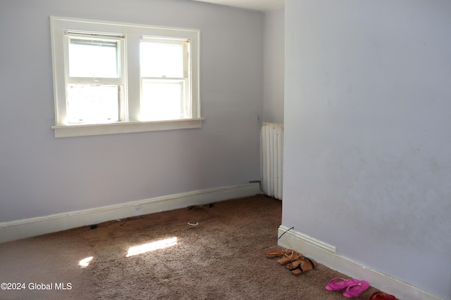 empty room featuring radiator heating unit and carpet floors