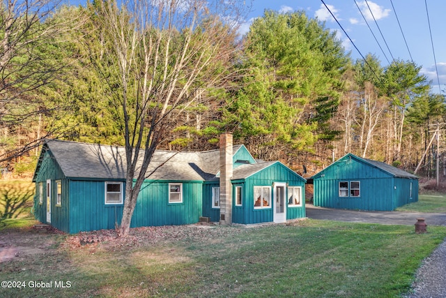 single story home with a front lawn and an outdoor structure