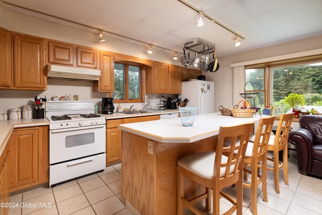 kitchen with light tile patterned flooring, a kitchen island, a textured ceiling, and white appliances