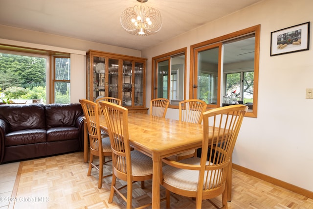 dining area with plenty of natural light, an inviting chandelier, and light parquet floors