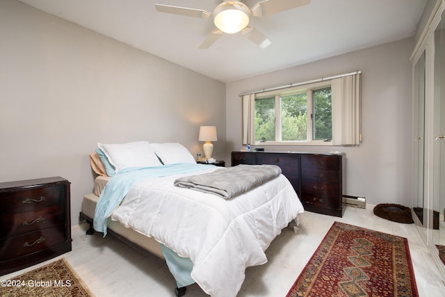 bedroom featuring ceiling fan, light hardwood / wood-style flooring, and a baseboard heating unit