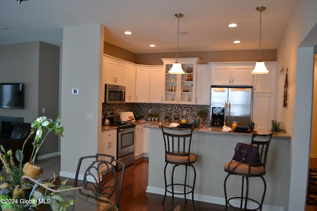 kitchen with dark wood-type flooring, stainless steel appliances, white cabinetry, and tasteful backsplash