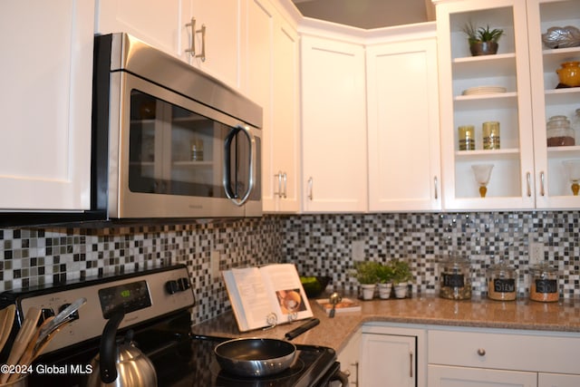 kitchen featuring appliances with stainless steel finishes, tasteful backsplash, light stone countertops, and white cabinets