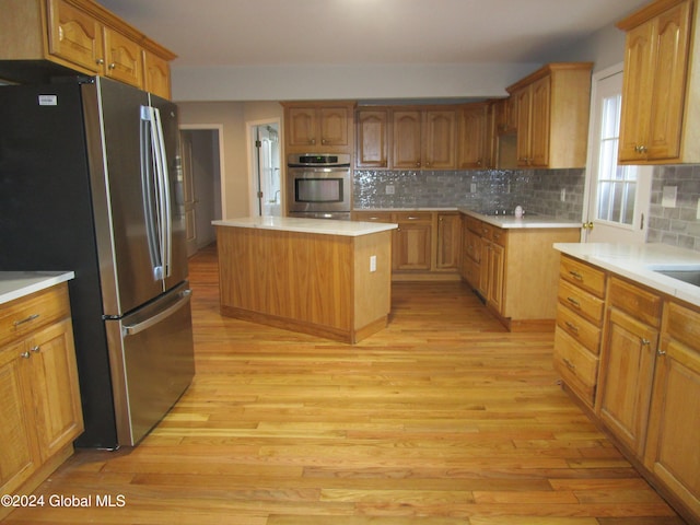 kitchen featuring decorative backsplash, a center island, light hardwood / wood-style floors, and appliances with stainless steel finishes