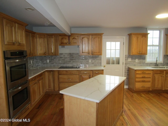 kitchen with wood-type flooring, decorative backsplash, and sink