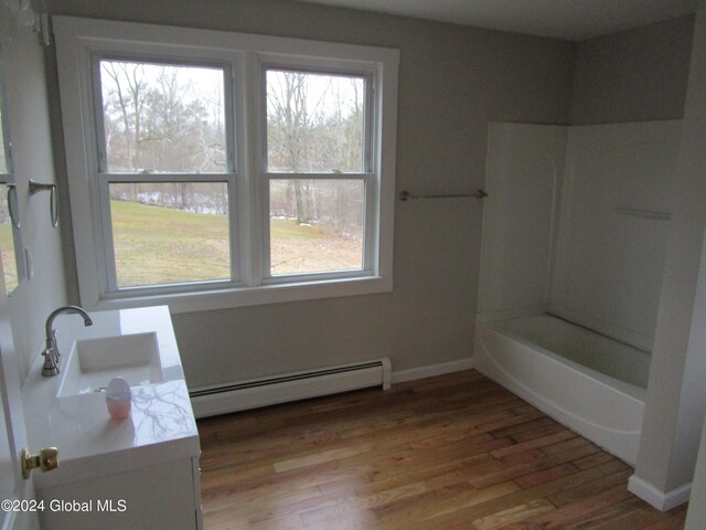 bathroom featuring vanity, baseboard heating, bathtub / shower combination, and hardwood / wood-style flooring