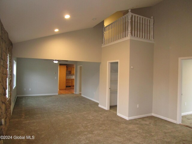 unfurnished living room with high vaulted ceiling and carpet floors