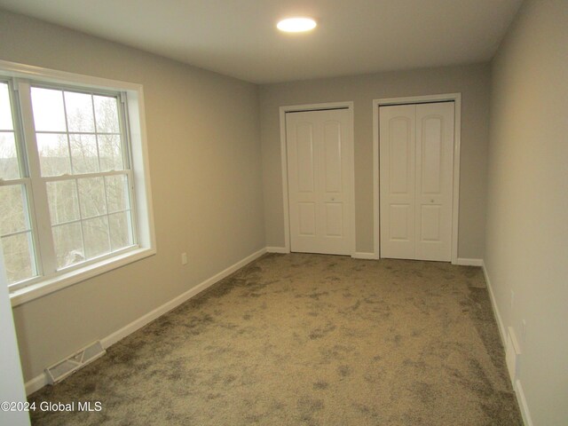 unfurnished bedroom with carpet and multiple closets