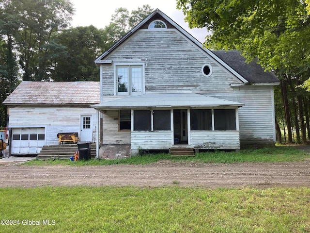 view of front of property with a sunroom, a front lawn, and a garage