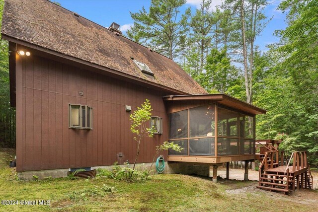 view of home's exterior with a sunroom and a lawn