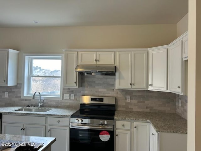 kitchen with stainless steel electric stove, sink, white cabinets, and light stone counters