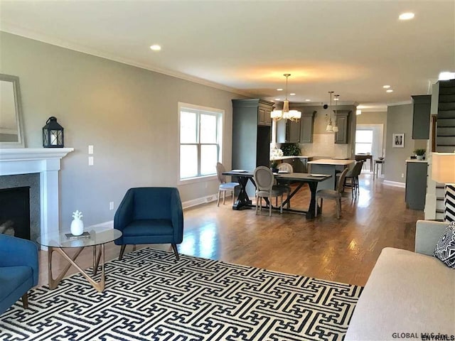 living room featuring dark hardwood / wood-style floors, ornamental molding, a fireplace, and an inviting chandelier