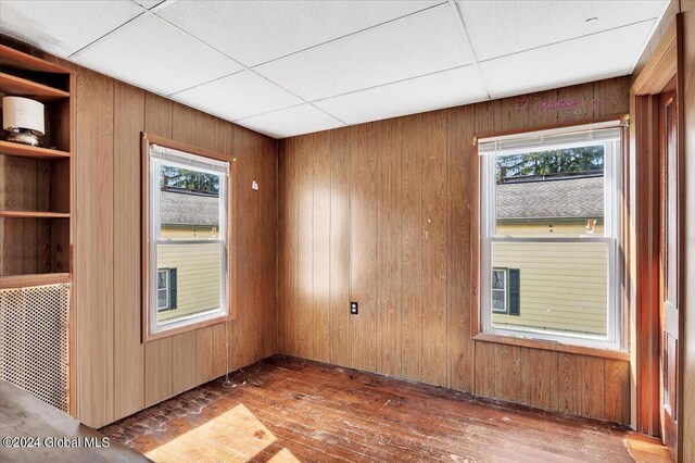 unfurnished room with a healthy amount of sunlight, wood walls, and hardwood / wood-style flooring