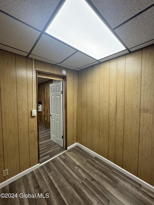 spare room with a paneled ceiling, wooden walls, and dark hardwood / wood-style floors