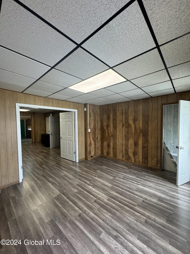 basement with hardwood / wood-style floors, a paneled ceiling, and wooden walls