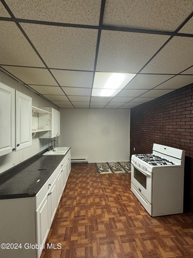 kitchen with white range with gas stovetop, dark parquet floors, a paneled ceiling, and white cabinetry