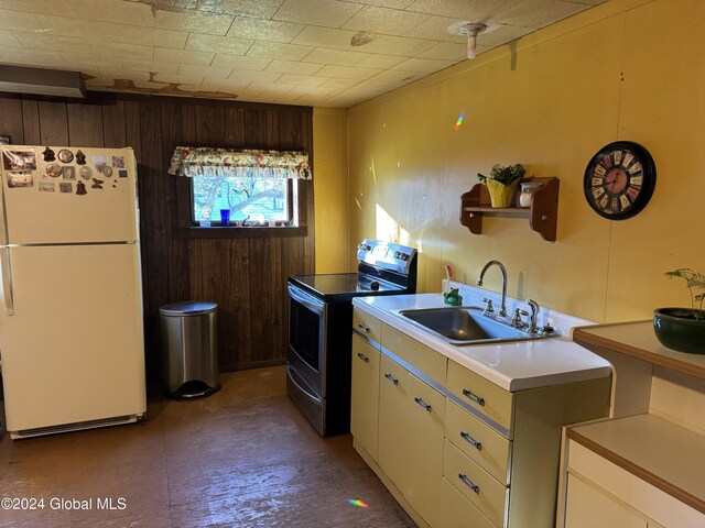 kitchen featuring electric stove, white refrigerator, wood walls, and sink