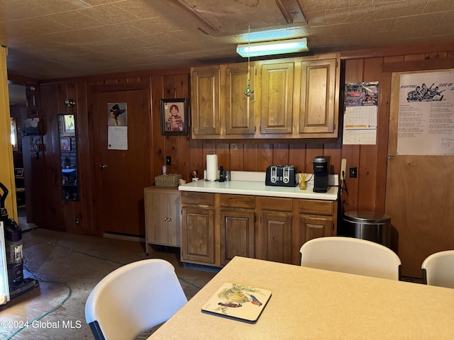 kitchen with light countertops, wood walls, and brown cabinetry