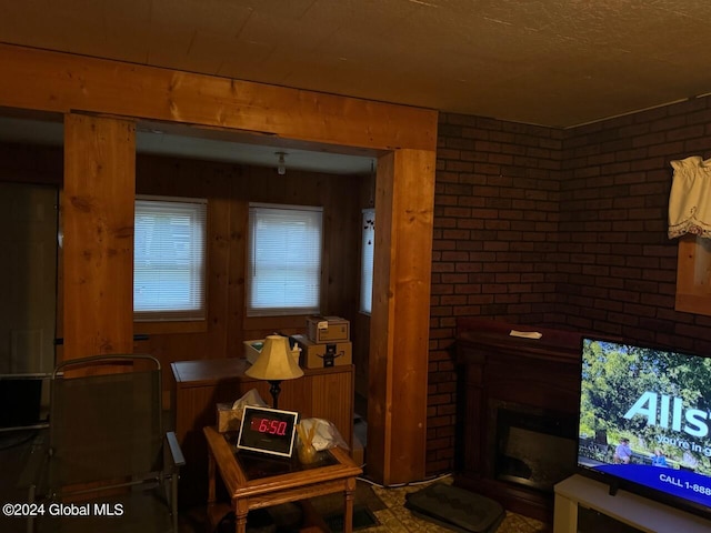 living area featuring a brick fireplace and brick wall