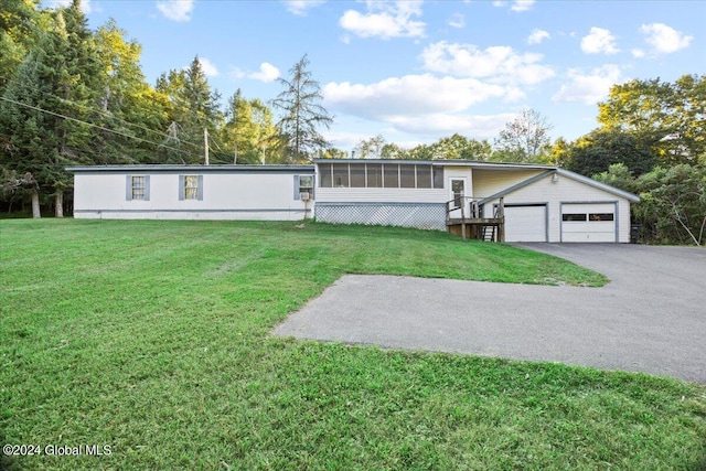 view of front of property with an outbuilding, a front yard, a garage, and a sunroom