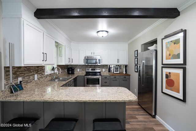 kitchen featuring appliances with stainless steel finishes, white cabinetry, kitchen peninsula, and sink