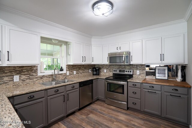 kitchen featuring white cabinets, crown molding, stainless steel appliances, sink, and dark wood-type flooring