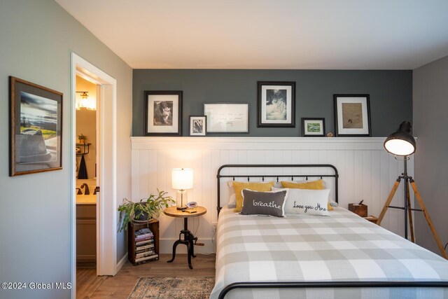 bedroom featuring ensuite bath and hardwood / wood-style floors