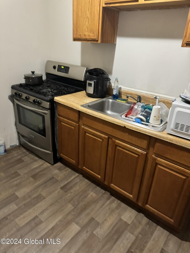 kitchen with dark wood-type flooring, sink, and stainless steel gas stove