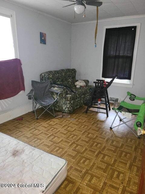 living room with ceiling fan, ornamental molding, and parquet flooring