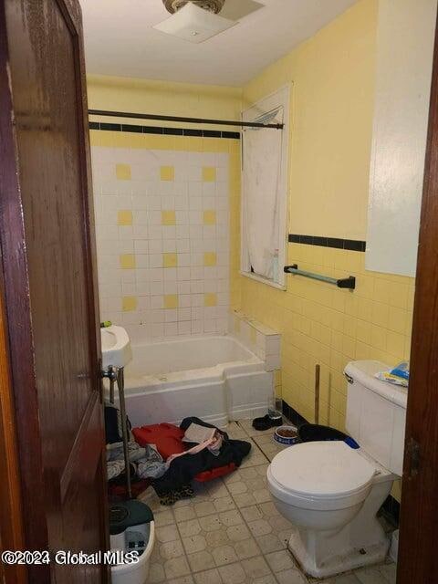 bathroom featuring tile walls and toilet