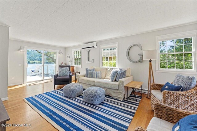 living room with a baseboard heating unit, crown molding, an AC wall unit, and light wood-type flooring