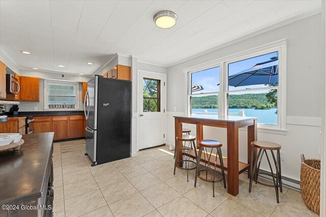 kitchen featuring crown molding, stainless steel appliances, baseboard heating, a water view, and light tile patterned flooring