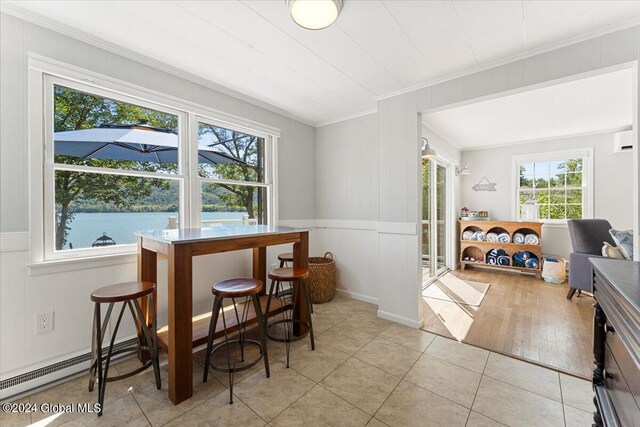 dining area featuring a water view, a baseboard heating unit, light hardwood / wood-style floors, and ornamental molding