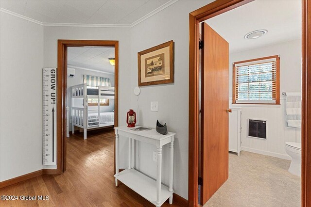 corridor with ornamental molding, heating unit, and light hardwood / wood-style floors