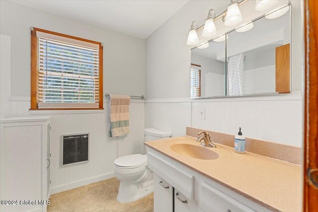 bathroom featuring toilet, heating unit, and vanity