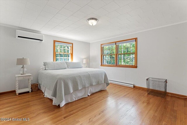 bedroom featuring light wood-type flooring, crown molding, a wall unit AC, and a baseboard radiator