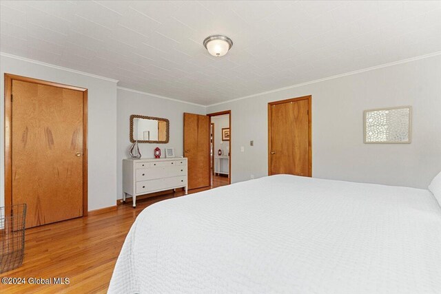 bedroom with light wood-type flooring and ornamental molding