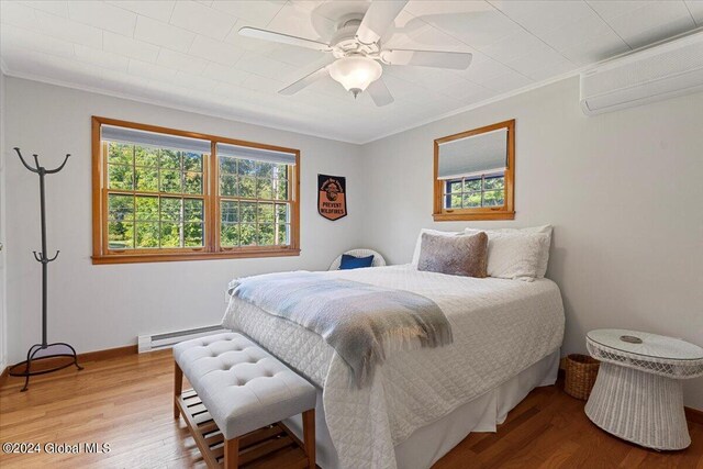 bedroom with ornamental molding, hardwood / wood-style flooring, a wall mounted air conditioner, and ceiling fan