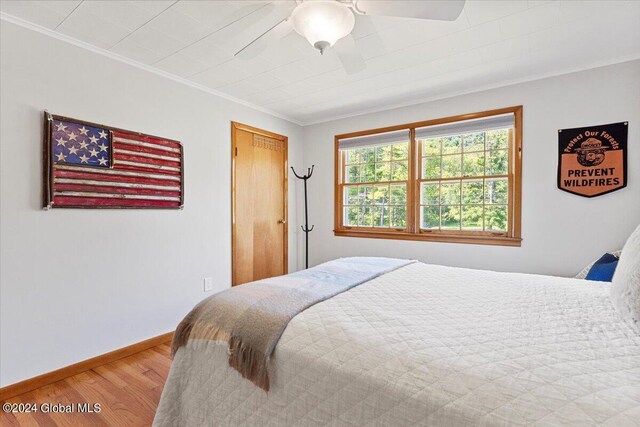 bedroom with a closet, ceiling fan, wood-type flooring, and ornamental molding