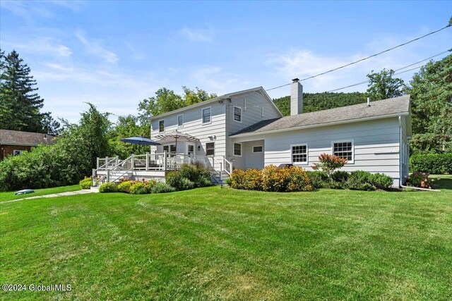 rear view of property with a lawn and a deck