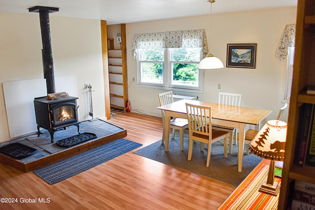 dining space with hardwood / wood-style flooring and a wood stove