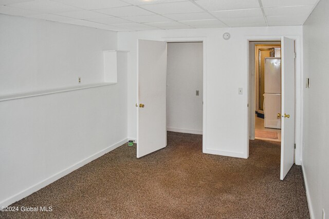 unfurnished bedroom featuring a closet, a paneled ceiling, and dark colored carpet