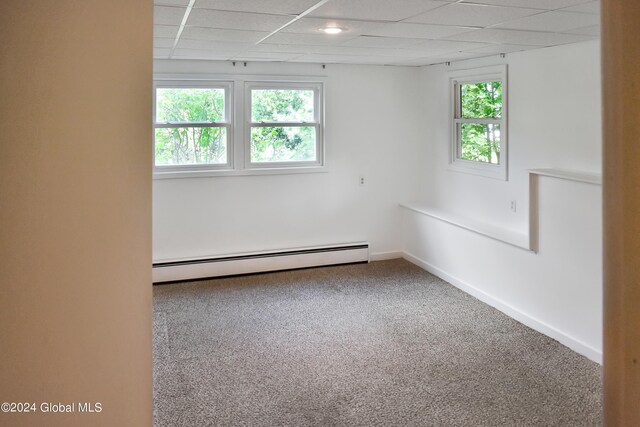 spare room featuring carpet floors, a baseboard heating unit, and a healthy amount of sunlight