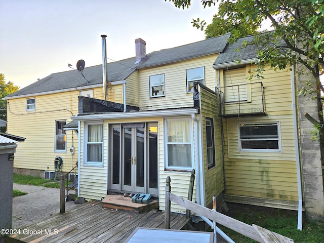 back of property with a chimney, a wooden deck, and french doors
