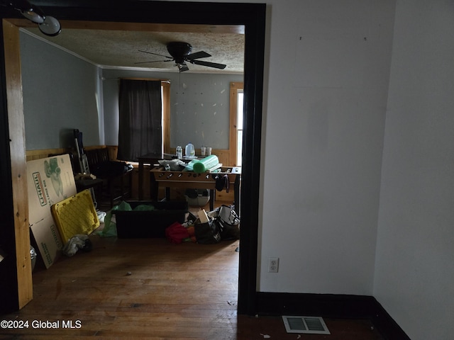 interior space featuring a textured ceiling, visible vents, a ceiling fan, and wood finished floors