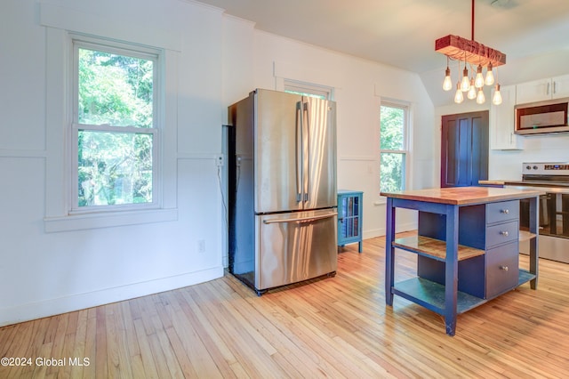 kitchen with hanging light fixtures, light wood-type flooring, stainless steel appliances, wooden counters, and ornamental molding